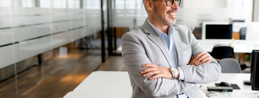 Successful authoritative confident mature grey-haired adult male entrepreneur businessman professional in formal wear standing at the modern home office, looking at camera